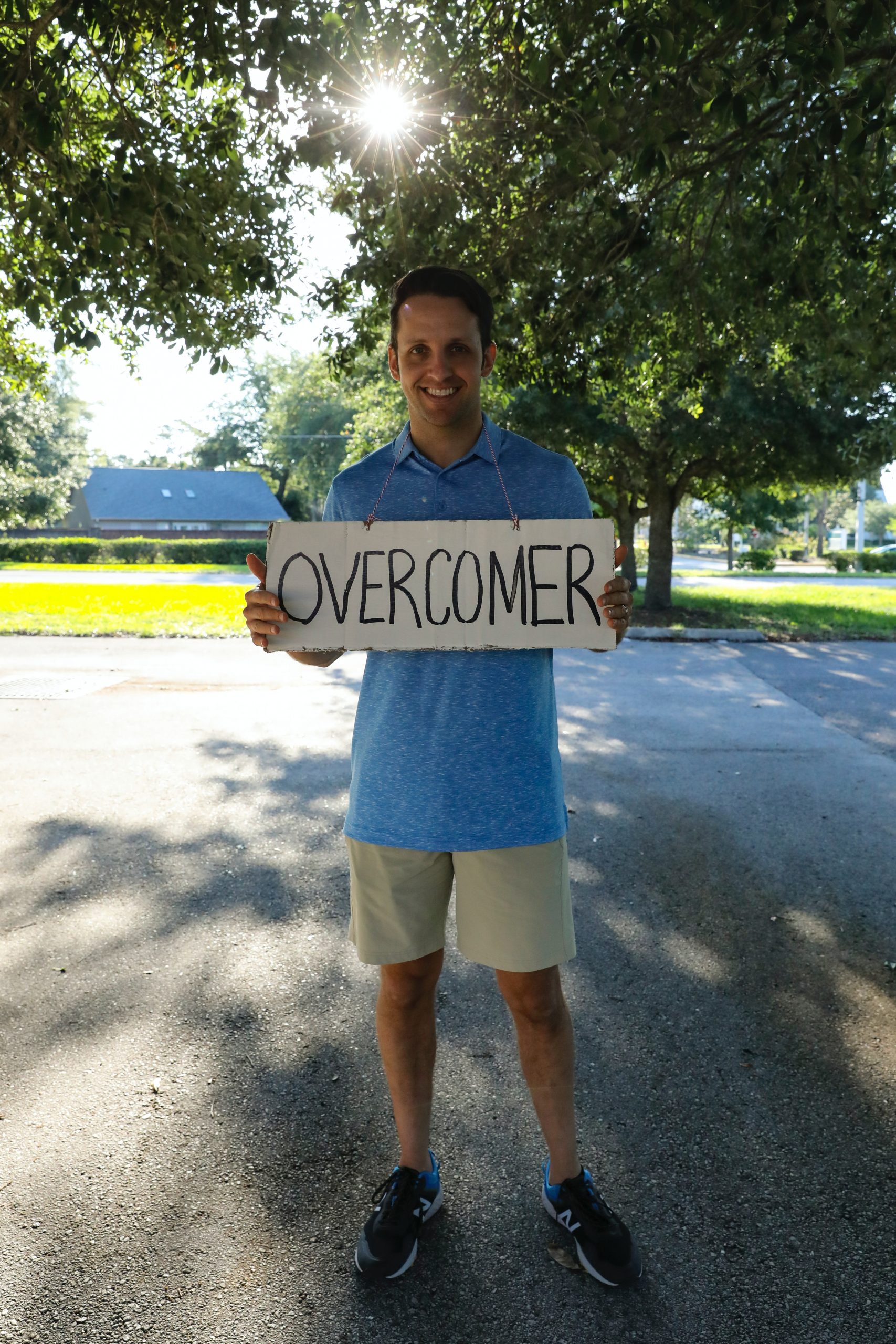 a man holding a sign that says "overcomer"